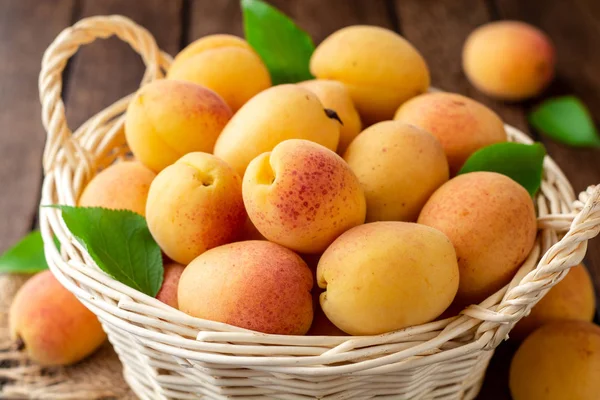 Hasır sepet koyu ahşap zemin üzerine taze kayısı. Seçici odak.