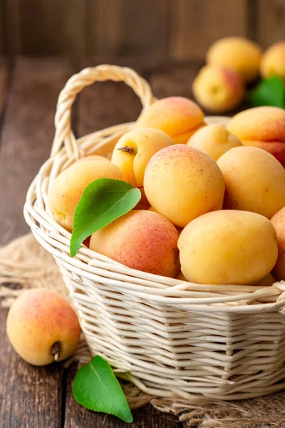 Hasır sepet koyu ahşap zemin üzerine taze kayısı. Seçici odak.