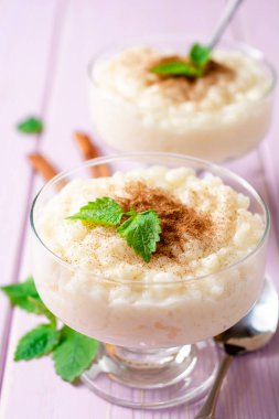 Tarçın ve nane hafif mor ahşap arka plan üzerinde sütlaç. Seçici odak.