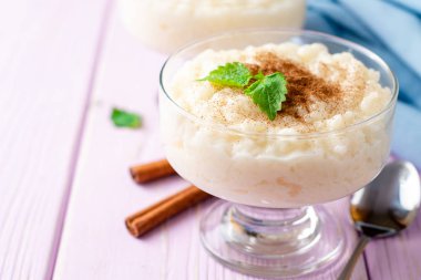 Tarçın ve nane hafif mor ahşap arka plan üzerinde sütlaç. Seçici odak.