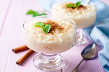 Tarçın ve nane hafif mor ahşap arka plan üzerinde sütlaç. Seçici odak.