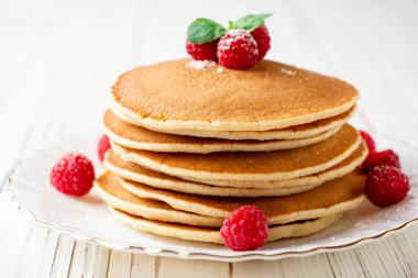 Ahududu ve beyaz ahşap zemin üzerine nane ile krep. Seçici odak.