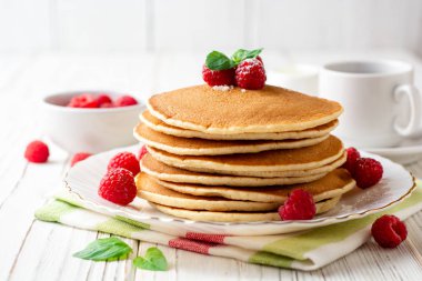 Ahududu ve beyaz ahşap zemin üzerine nane ile krep. Seçici odak.