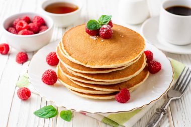 Ahududu ve beyaz ahşap zemin üzerine nane ile krep. Seçici odak.