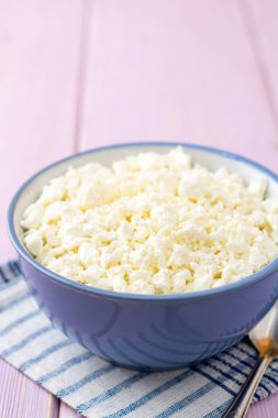 Mor ahşap zemin üzerine mavi kase süzme peynir. Seçici odak.