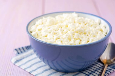 Mor ahşap zemin üzerine mavi kase süzme peynir. Seçici odak.