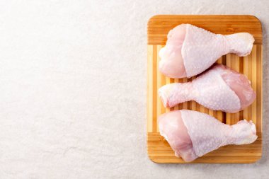 Gri taş zemin üzerine kesme tahtası üzerinde çiğ tavuk budu. Üstten görünüm. Kopya alanı.