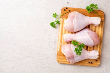 Baharatlar ve otlar kesme tahtası üzerinde çiğ tavuk budu. Üstten görünüm. Kopya alanı.