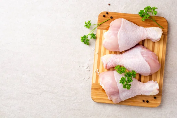 Baharatlar ve otlar kesme tahtası üzerinde çiğ tavuk budu. Üstten görünüm. Kopya alanı.