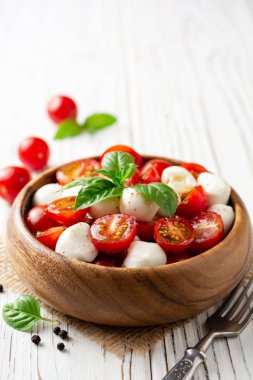 İtalyan caprese salatası kiraz domates, mozzarella peyniri ve fesleğen Beyaz ahşap zemin üzerinde. Seçici odak.
