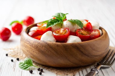 İtalyan caprese salatası kiraz domates, mozzarella peyniri ve fesleğen Beyaz ahşap zemin üzerinde. Seçici odak.