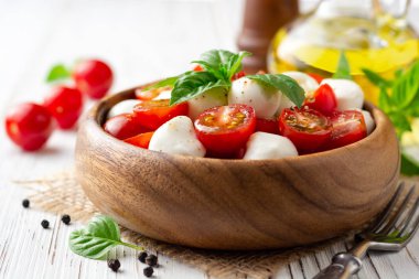 İtalyan caprese salatası kiraz domates, mozzarella peyniri ve fesleğen Beyaz ahşap zemin üzerinde. Seçici odak.
