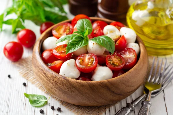 İtalyan caprese salatası kiraz domates, mozzarella peyniri ve fesleğen Beyaz ahşap zemin üzerinde. Seçici odak.