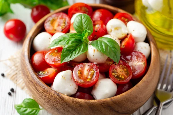 İtalyan caprese salatası kiraz domates, mozzarella peyniri ve fesleğen Beyaz ahşap zemin üzerinde. Seçici odak.