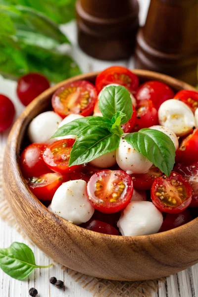 İtalyan caprese salatası kiraz domates, mozzarella peyniri ve fesleğen Beyaz ahşap zemin üzerinde. Seçici odak.
