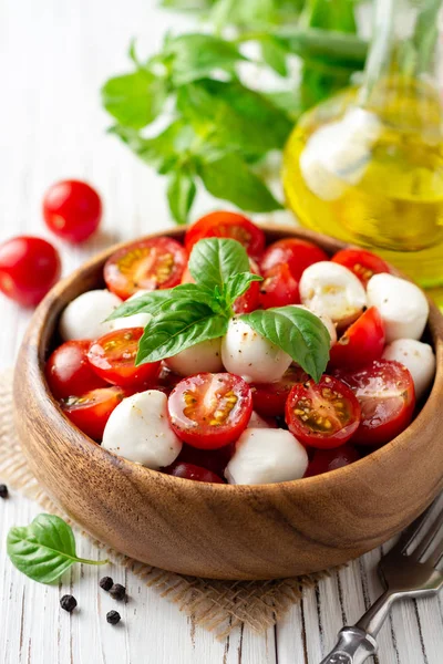 İtalyan caprese salatası kiraz domates, mozzarella peyniri ve fesleğen Beyaz ahşap zemin üzerinde. Seçici odak.
