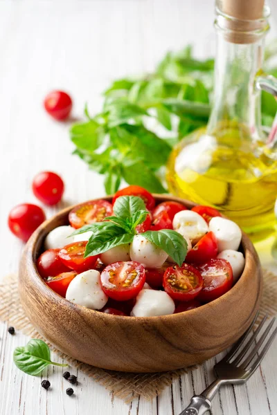 İtalyan caprese salatası kiraz domates, mozzarella peyniri ve fesleğen Beyaz ahşap zemin üzerinde. Seçici odak.