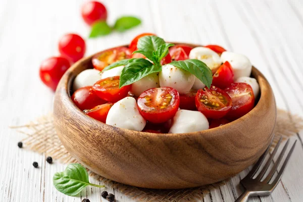 İtalyan caprese salatası kiraz domates, mozzarella peyniri ve fesleğen Beyaz ahşap zemin üzerinde. Seçici odak.