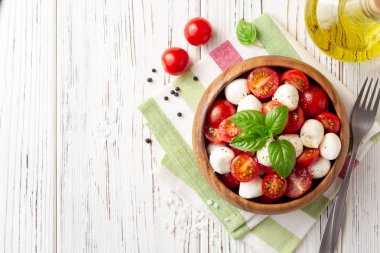İtalyan caprese salatası kiraz domates, mozzarella peyniri ve fesleğen Beyaz ahşap zemin üzerinde. Üstten görünüm. Kopya alanı.