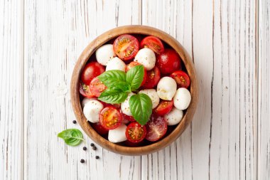 İtalyan caprese salatası kiraz domates, mozzarella peyniri ve fesleğen Beyaz ahşap zemin üzerinde. Üstten görünüm. Kopya alanı.