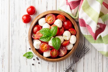 İtalyan caprese salatası kiraz domates, mozzarella peyniri ve fesleğen Beyaz ahşap zemin üzerinde. Üstten görünüm. Kopya alanı.