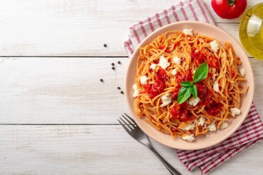 Spagetti makarna domates sosu, mozzarella peyniri ve plaka Beyaz ahşap zemin üzerinde taze fesleğen. Üstten görünüm. Kopya alanı.