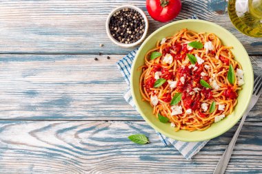 Spagetti makarna domates sosu, mozzarella peyniri ve taze fesleğen ile beyaz-mavi vintage ahşap arka plan üzerinde bırakır. Üstten görünüm. Kopya alanı.