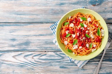 Spagetti makarna domates sosu, mozzarella peyniri ve taze fesleğen ile beyaz-mavi vintage ahşap arka plan üzerinde bırakır. Üstten görünüm. Kopya alanı.