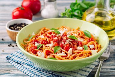 Spagetti makarna domates sosu, mozzarella peyniri ve taze fesleğen ile beyaz-mavi vintage ahşap arka plan üzerinde bırakır. Seçici odak.