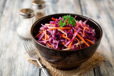 Kırmızı ve beyaz lahana ve havuç kase vintage ahşap zemin üzerine taze lahana salatası. Seçici odak.