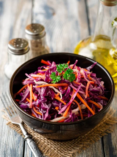 Fresh coleslaw salad with red and white cabbage and carrots in bowl on vintage wooden background. Selective focus.