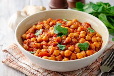 Baharatlı nohut Chana Masala ahşap masa üzerinde bir kapta köri. Geleneksel Hint yemeği. Seçici odak.