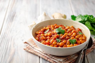 Baharatlı nohut Chana Masala ahşap masa üzerinde bir kapta köri. Geleneksel Hint yemeği. Seçici odak.