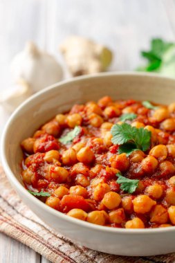 Baharatlı nohut Chana Masala ahşap masa üzerinde bir kapta köri. Geleneksel Hint yemeği. Seçici odak.