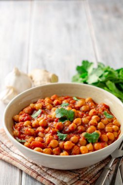 Baharatlı nohut Chana Masala ahşap masa üzerinde bir kapta köri. Geleneksel Hint yemeği. Seçici odak.