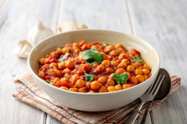 Baharatlı nohut Chana Masala ahşap masa üzerinde bir kapta köri. Geleneksel Hint yemeği. Seçici odak.