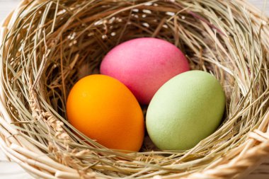 Ahşap arka planda hasır sepet renkli Paskalya yumurtası. Seçici odak.