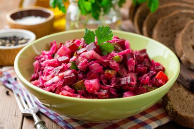 Geleneksel Rus salata salata ile haşlanmış sebzeler, turşu salatalık ve lahana turşusu ahşap masada kase. Seçici odak.