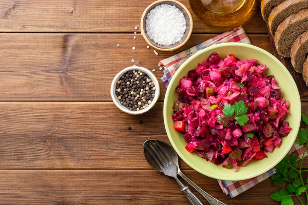 Geleneksel Rus salata salata ile haşlanmış sebzeler, turşu salatalık ve lahana turşusu ahşap masada kase. Üst görünüm. Boşluk Kopyala.