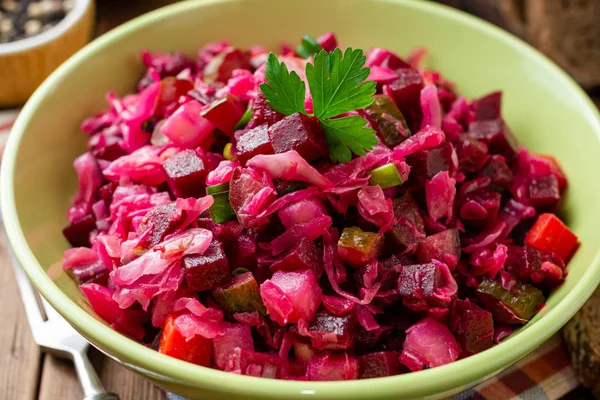 Geleneksel Rus salata salata ile haşlanmış sebzeler, turşu salatalık ve lahana turşusu ahşap masada kase. Seçici odak.