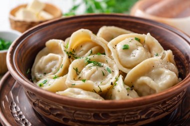 Beyaz ahşap masa üzerinde seramik kase tereyağı ve yeşillik ile geleneksel Rus ev yapımı et köfte pelmeni. Seçici odaklama.