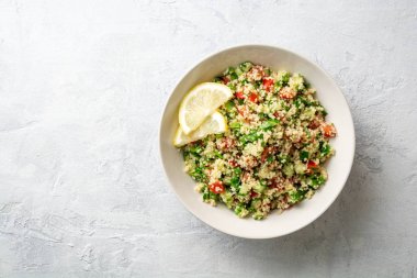 Beton arka plan üzerinde kuskus, sebze ve yeşillik ile Geleneksel Arap Salatası Tabbouleh. Üst te. Kopyalama alanı.