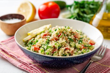 Beton arka plan üzerinde kuskus, sebze ve yeşillik ile Geleneksel Arap Salatası Tabbouleh. Seçici odaklama.