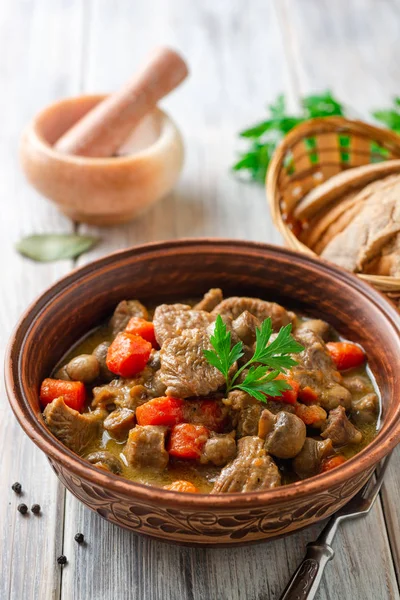 Turkey meat stew with mushrooms and vegetables in ceramic bowl on wooden table. Selective focus.