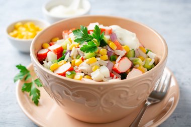 Yengeç çubuklu salata, tatlı mısır, salatalık, haşlanmış yumurta, soğan ve pirinç. Rus mutfağı. Seçici odak.