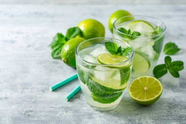 Beton arka planda cam kireç ve nane ile taze Mojito kokteyl. Soğuk serinletici içecek. Seçici odak.
