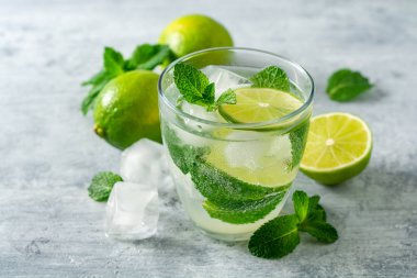 Beton arka planda cam kireç ve nane ile taze Mojito kokteyl. Soğuk serinletici içecek. Seçici odak.
