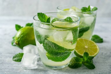 Beton arka planda cam kireç ve nane ile taze Mojito kokteyl. Soğuk serinletici içecek. Seçici odak.