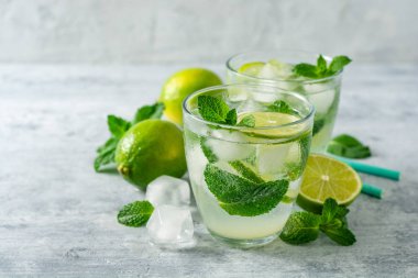 Beton arka planda cam kireç ve nane ile taze Mojito kokteyl. Soğuk serinletici içecek. Seçici odak.