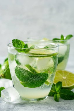 Beton arka planda cam kireç ve nane ile taze Mojito kokteyl. Soğuk serinletici içecek. Seçici odak.